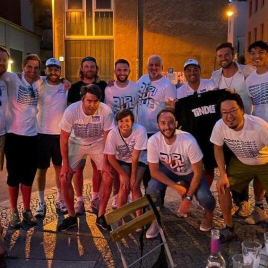 A group of smiling people posing together outdoors during an evening gathering.